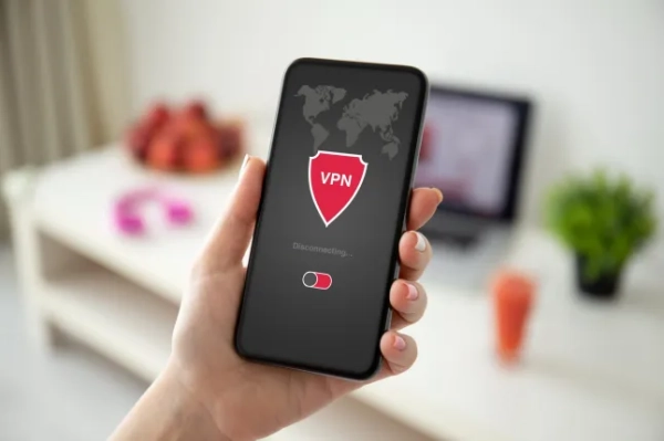 Безкоштовний VPN-додаток таємно стежить за екранами користувачів, перш ніж викрасти їхні банківські рахунки. Жіноча рука тримає телефон із застосунком VPN створення інтернет-протоколів для захисту приватної мережі фонова кімната в будинку