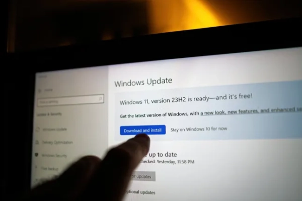 Мільйони користувачів Windows 10 закликають вжити заходів, перш ніж Microsoft припинить підтримку цієї операційної системи. Палець, що вказує на екран Windows Update на ноутбуці, виділяє кнопку «Завантажити та встановити» для Windows 11