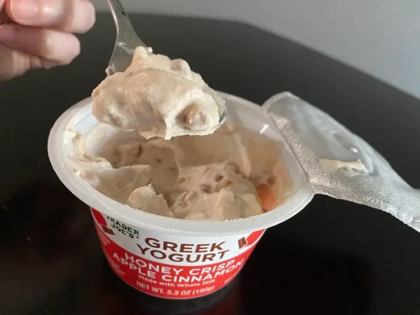 Ложка, що бере йогурт з контейнера йогурту з яблуком і корицею від Trader Joe's.
