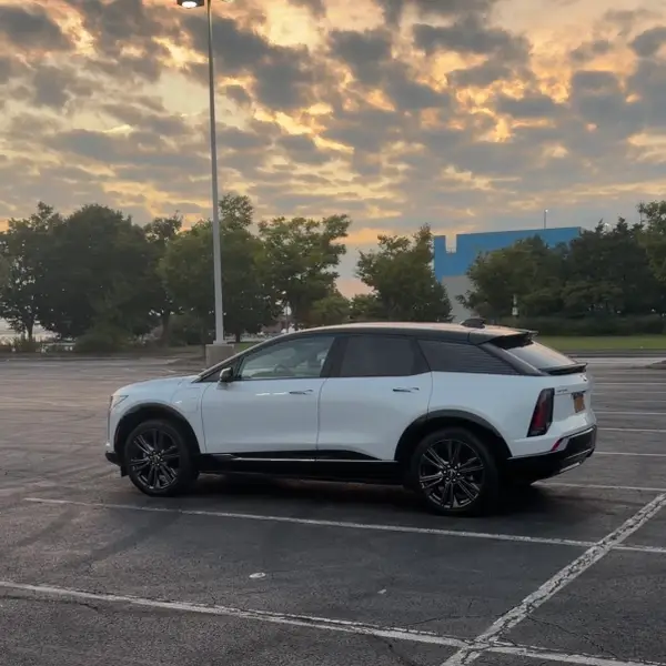 Білий Cadillac Optiq припаркований на великій стоянці в сутінках.