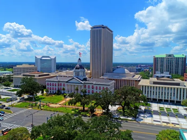 Florida State Capitol complex in Tallahassee with the historic domed capitol, tower, streets, and blue sky.