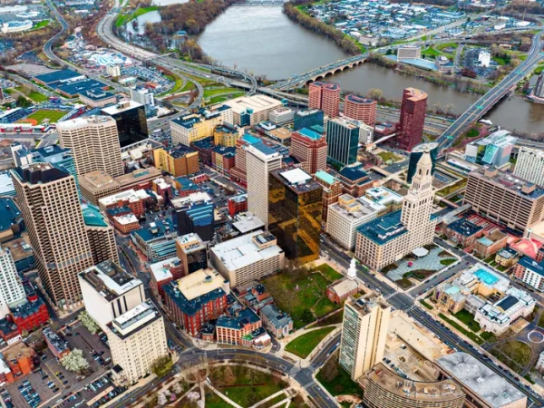 Aerial view of downtown Hartford skyscrapers beside the Connecticut River and multiple bridges.