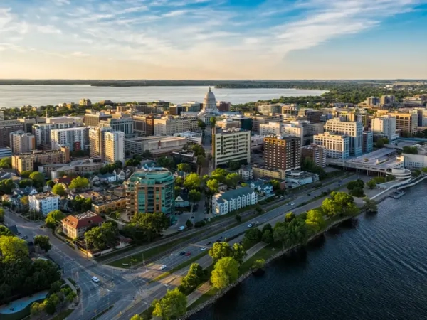Aerial view of downtown Madison with the Wisconsin State Capitol between lakes in warm evening light.