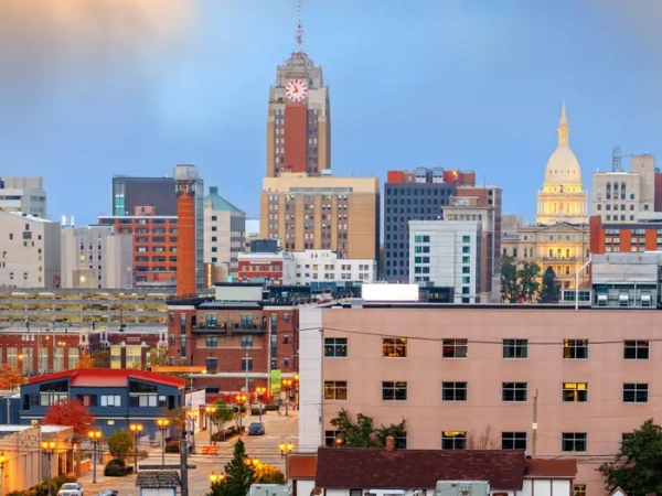 Downtown Lansing skyline at dusk with Boji Tower and the illuminated Michigan State Capitol dome.