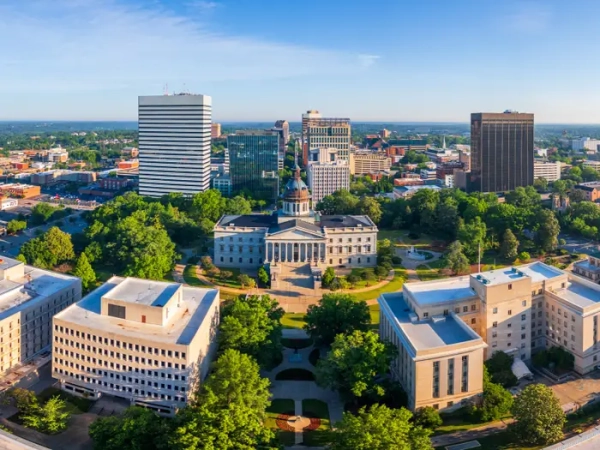 Aerial view of the South Carolina State House surrounded by trees and downtown Columbia buildings.