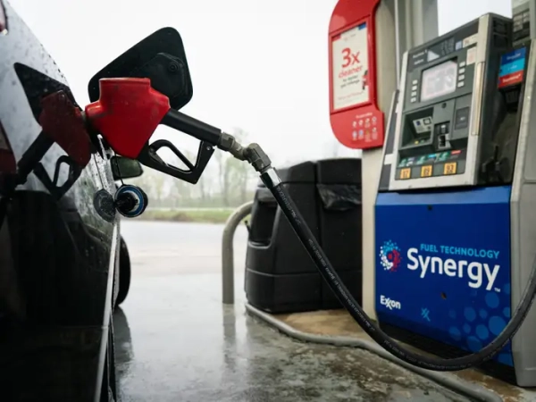 A gas pump is inserted into a black car.